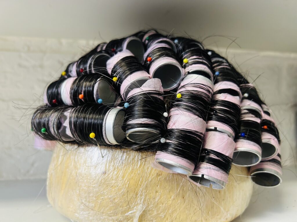 In het atelier van Just Hair staat een haarwerk in de krullers om een mooi krullend kapsel te creëren.