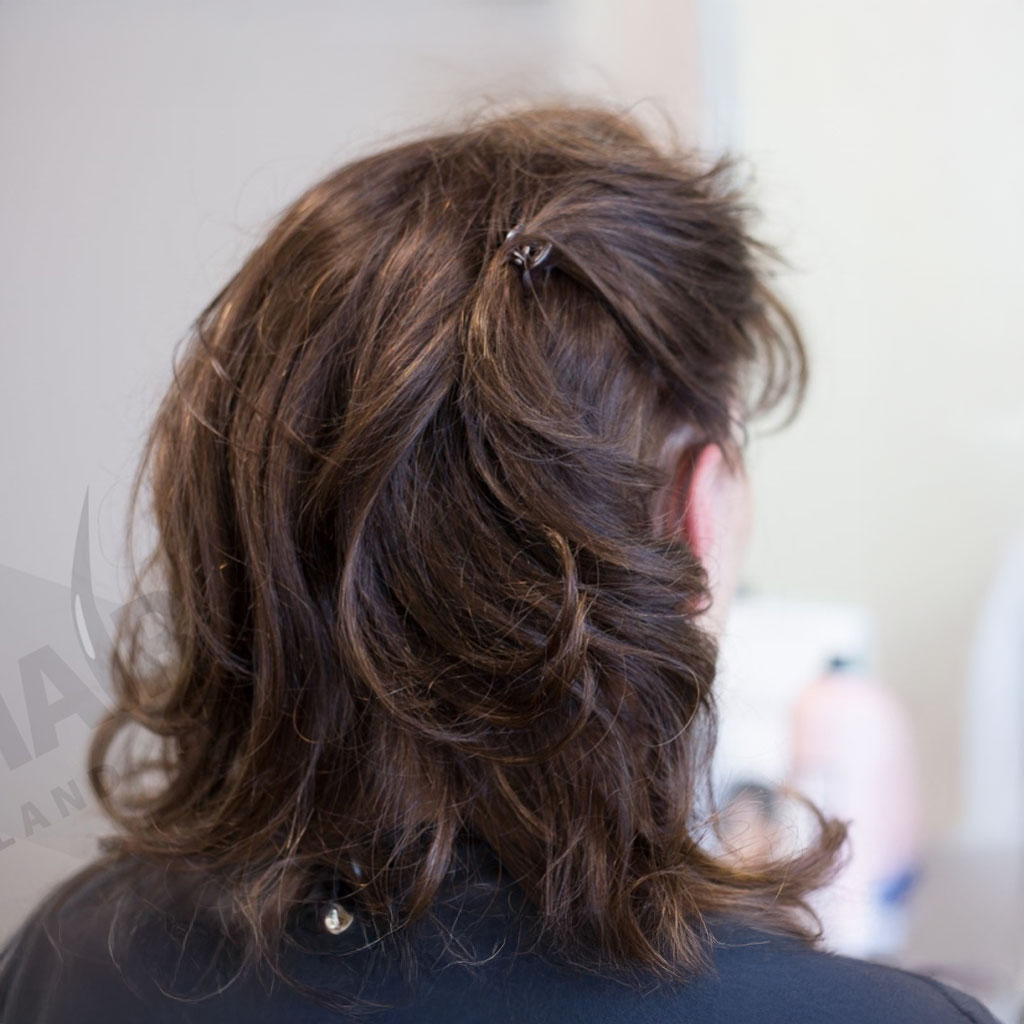 Een vrouw nu weer met een dikke bos bruin haar nadat Just Hair een haarwerk op maat heeft geplaatst.